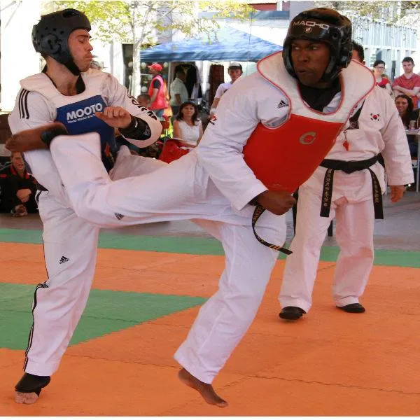 Two students sparring, one landing a back kick.