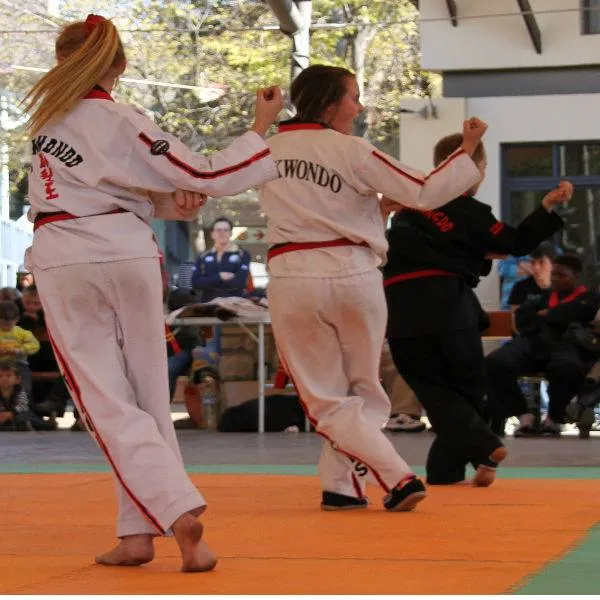 Two students performing a partner pattern outdoors in front of a KJD banner.