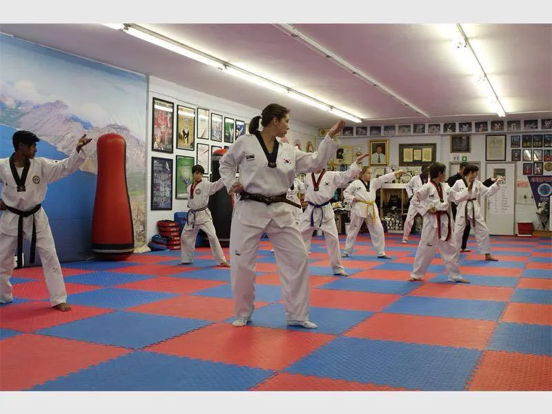 Adult students training in formation across the red and blue mats.