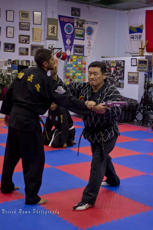 A Hapkido student practising a gun disarm against an instructor.