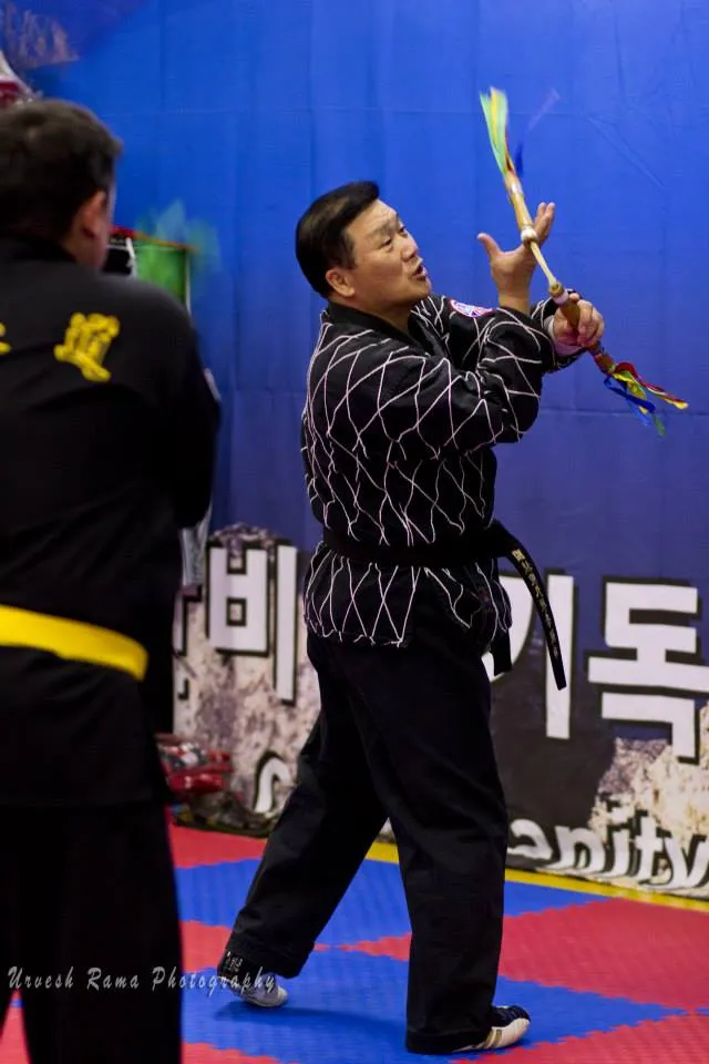 Grandmaster Eun Woo Lee demonstrating with nunchaku in the dojang.