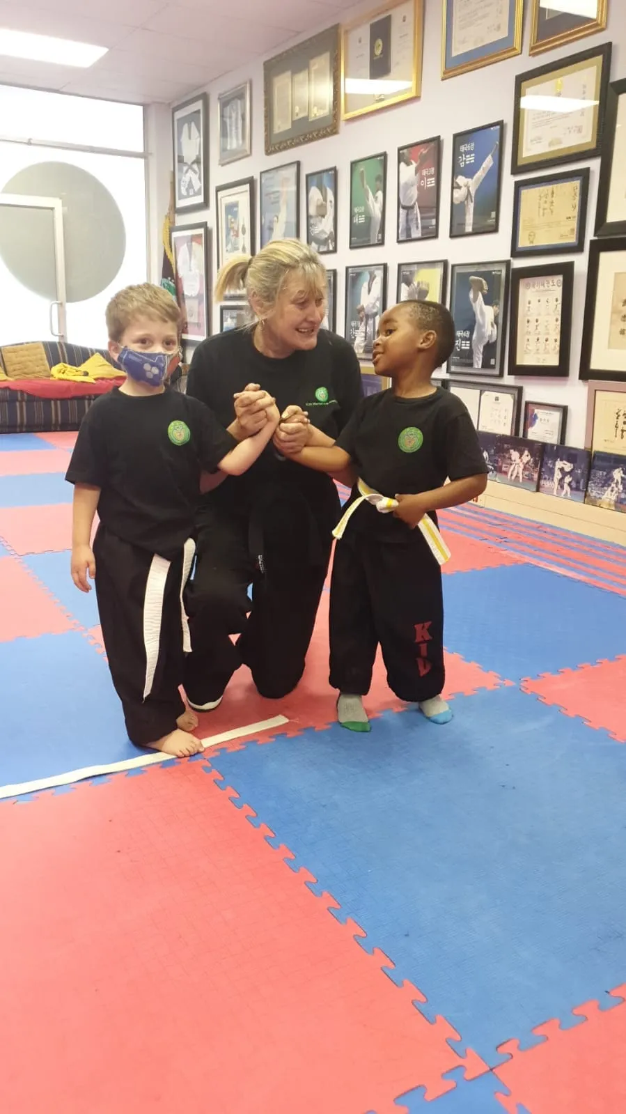 Samonim Lorraine Lee kneeling between two young students in the dojang.
