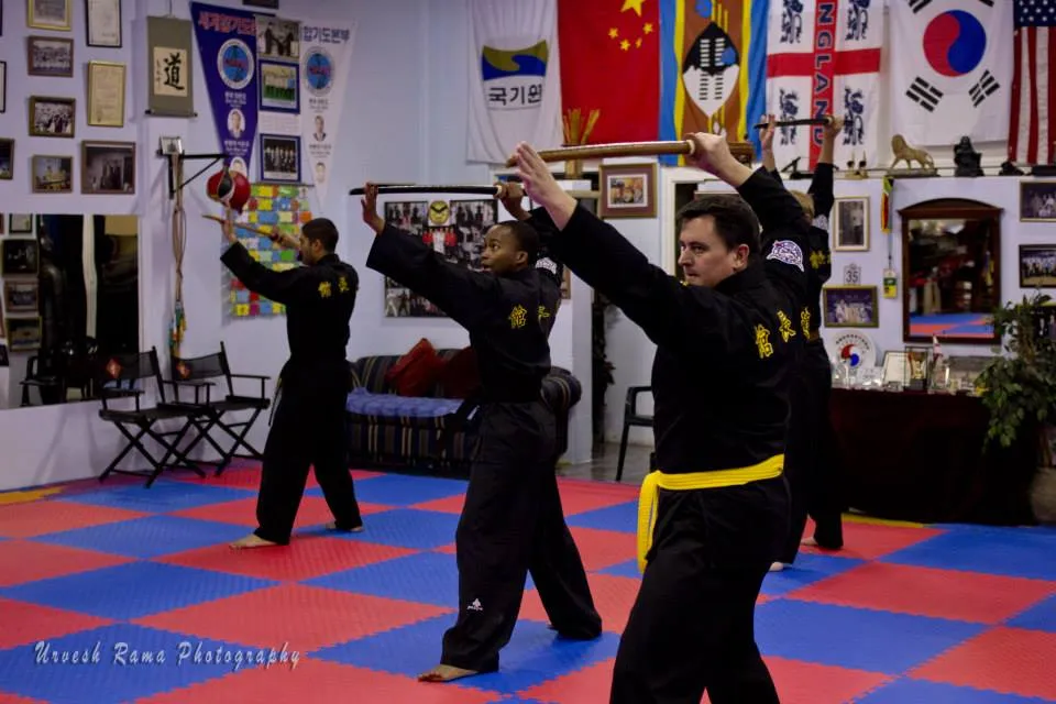 A student performing a sword pattern in traditional uniform.