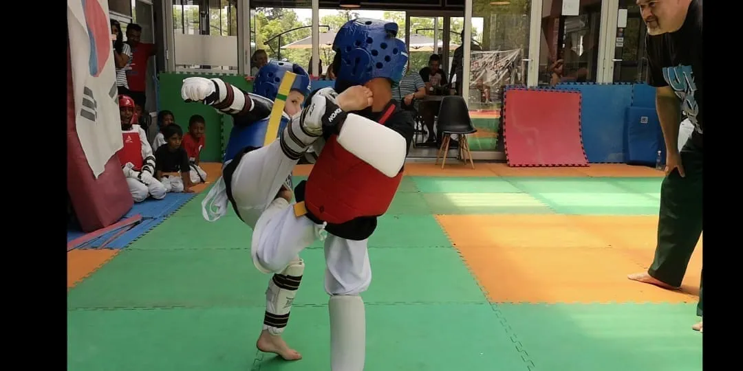 Two young students sparring in protective gear.
